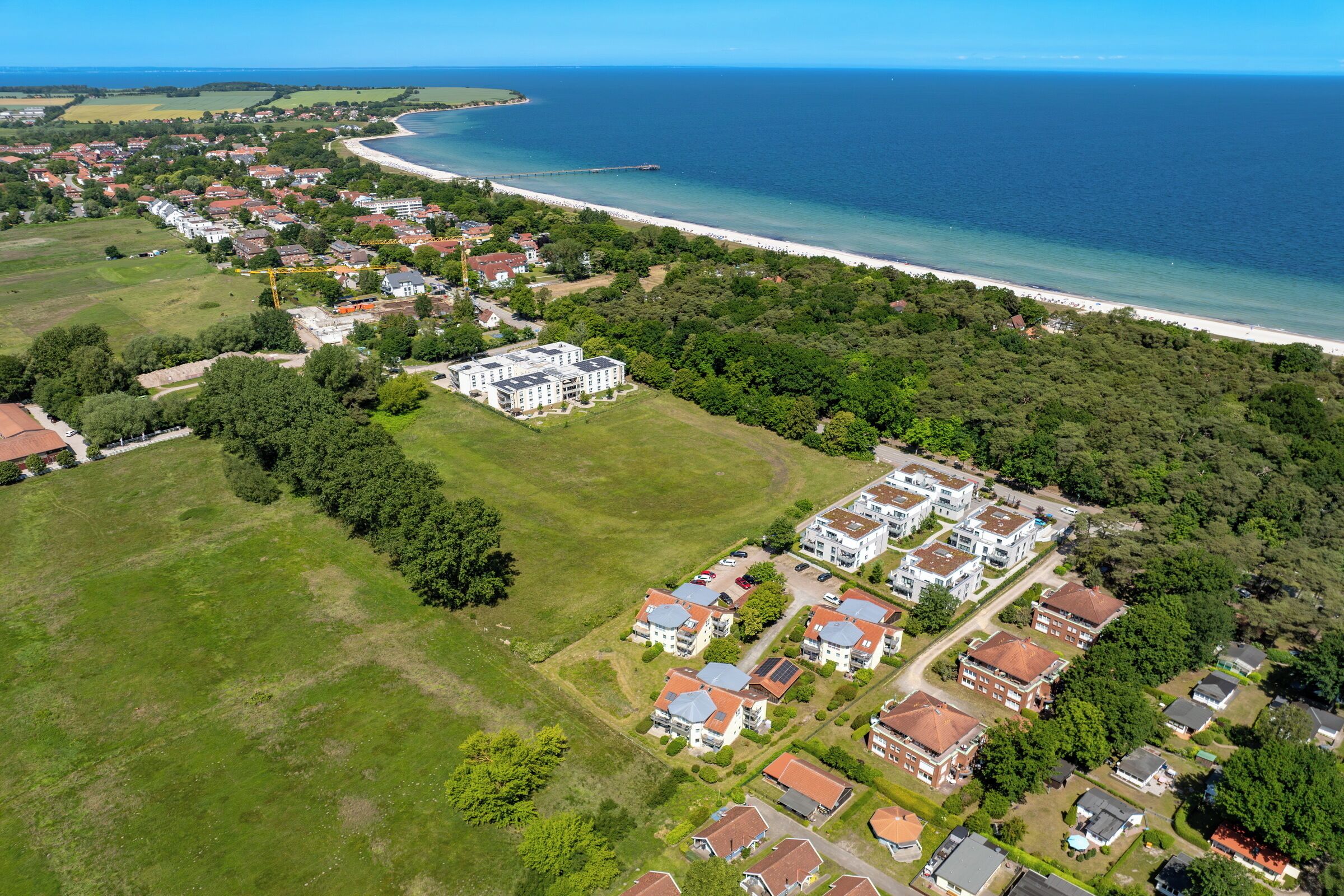 Vista aérea de una zona residencial costera con casas, una playa y un muelle.