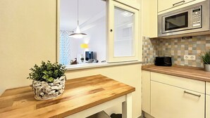 A modern kitchen with a wooden countertop, a built-in microwave, and a window with a view of the outside.