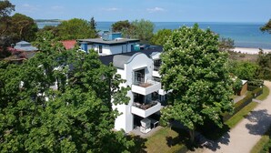 A modern multi-story building with balconies overlooking a beach and a body of water.