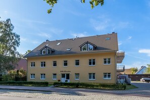 Un bâtiment à deux étages, doté d’un toit recouvert de tuiles, de nombreuses fenêtres et d’un petit balcon à l’étage supérieur.