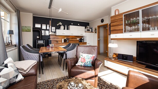 A modern living room with a sofa, armchairs, a coffee table, and a television. - Villa Bernstein Wohnung 06 (Ostseebad Boltenhagen)