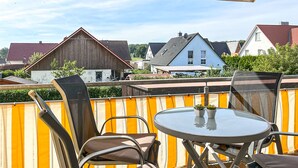 A patio with a table and chairs, a wooden fence, and houses in the background. - Villa Bernstein Wohnung 06 (Ostseebad Boltenhagen)
