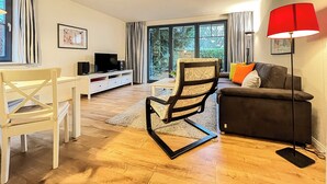 Una sala de estar moderna con una mesa de comedor blanca, una silla negra, un sofá gris y una lámpara de pie roja.
