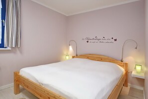 Quarto com cama de madeira, duas luminárias de cabeceira e um adorno na parede.
