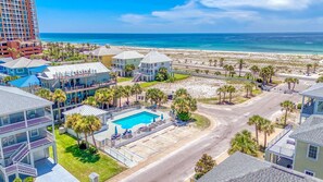 A resort with a swimming pool, beachfront view, and multiple buildings with balconies.