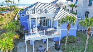 Une propriété de deux étages située en bord de mer, dotée d’un balcon, d’un espace salon extérieur et offrant une vue sur l’océan.