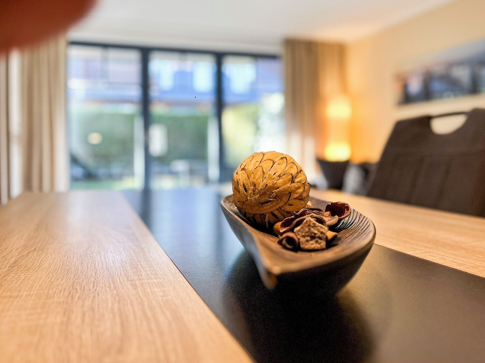 Una mesa de madera con un bol que contiene una nuez y ramas de canela.