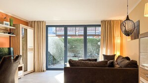 Een moderne woonkamer met een bank, een televisie en een eethoek met een tafel en stoelen.