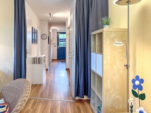 Ein Flur mit Holzboden, einer Couch, einem Schrank und einer Pflanze.