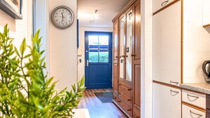 A hallway with wooden cabinets, a clock, and a door leading to a room.