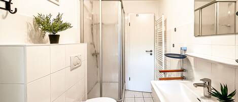 A modern bathroom with a toilet, sink, and shower.