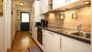 A modern kitchen with white cabinets, a stainless steel sink, and a built-in oven. - Papillon Wohnung 10-8 (Ostseebad Boltenhagen)