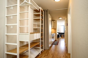 Ein Flur mit einem weißen Schrank, Regalen und Holzdielen.
