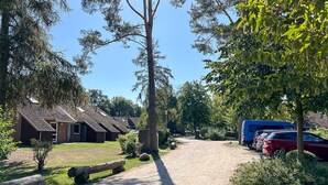 Ein Campingplatz mit Hütten, einem Kiesweg und abgestellten Fahrzeugen.