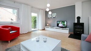 A modern living room with a red sofa, white coffee table, and a television. - Urlauberdorf Wohnung 21b (Ostseebad Boltenhagen)