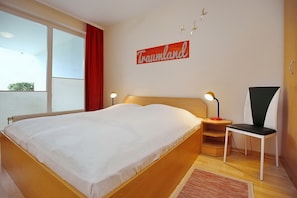 Ein Hotelzimmer mit einem großen Bett, einem Nachttisch mit Lampe, einem Sessel und einem Fenster mit Blick.