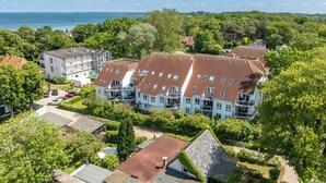 Een woonwijk met een rij huizen, rode pannendaken en uitzicht op zee.