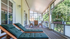 Un espacio al aire libre cubierto con sillones de madera y una mesa.