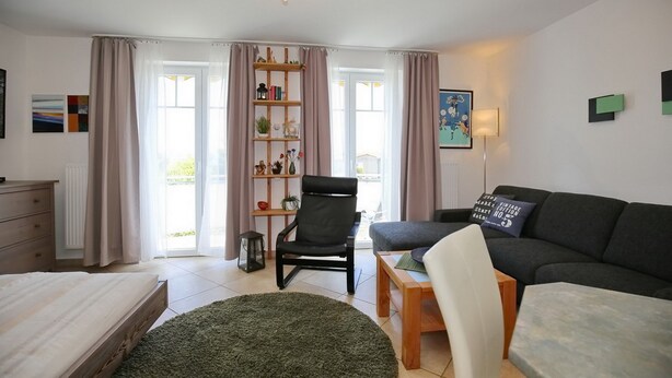 Un salon moderne comprenant un canapé, un fauteuil, une table basse et une bibliothèque.