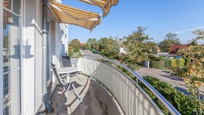 Un balcon avec un auvent rayé, une chaise et une table.