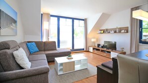 Ein modernes Wohnzimmer mit Sofa, Couchtisch, Fernseher und Essbereich.
