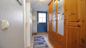 Ein Flur mit einem Holzschrank, einer blauen Tür und einem grauen Teppich.