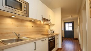 Een moderne keuken met een ingebouwde magnetron, een roestvrijstalen spoelbak en een houten aanrecht.