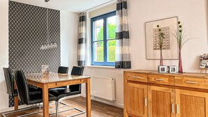 Een moderne keuken met een houten tafel, stoelen en een raam met gordijnen.