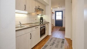 Een moderne keuken met lichte houten kastjes, een roestvrijstalen spoelbak en een inbouwoven.