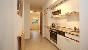 A modern kitchen with white cabinets, a stainless steel sink, and a built-in oven. - Papillon Wohnung 04-2 (Ostseebad Boltenhagen)