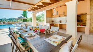 A dining area with a pool view, wooden beams, and a tiled backsplash. - Country house in Mallorca Cas Cuni with pool (Felanitx)