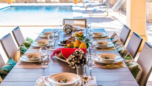 A dining table set for a meal with a view of a swimming pool in the background. - Country house in Mallorca Cas Cuni with pool (Felanitx)