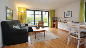 Ein modernes Wohnzimmer mit Sofa, Couchtisch und Essbereich mit Stuhl und Tisch.