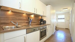 Eine moderne Küche mit weißen Schränken, Edelstahlgeräten und einer Holz Arbeitsplatte.
