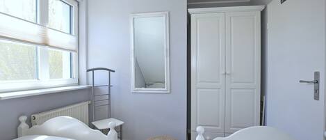 Een slaapkamer met twee bedden, een grote spiegel, een kast en een radiator.