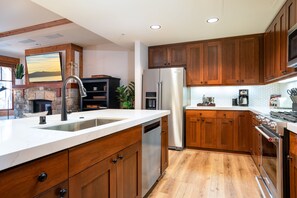 A modern kitchen with wooden cabinets, stainless steel appliances, and a large island with a sink.