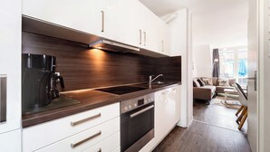 Een moderne keuken met witte kasten, een donker aanrecht en roestvrijstalen apparatuur.