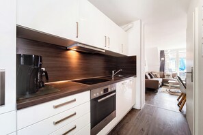 A modern kitchen with white cabinets, a dark countertop, and stainless steel appliances. - Papillon Wohnung 04-6 (Ostseebad Boltenhagen)