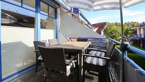 Un balcone con mobili in vimini e ombrelloni a righe.
