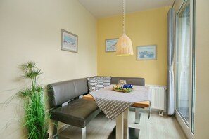 Ein gemütlicher Essbereich mit einem Tisch für zwei Personen, einer Bank und einem Blumentopf.