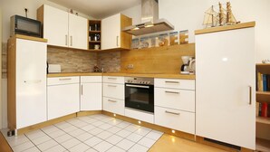 Una cocina moderna con armarios blancos, horno empotrado, microondas y encimera de madera.