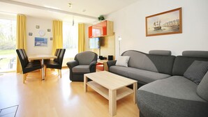 Una sala de estar moderna con un sofá gris, una mesa de centro de madera y un comedor con una mesa y sillas.