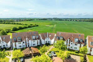 A residential area with multiple two-story houses featuring red-tiled roofs and white walls. - Sünnslag Wohnung 019 (Ostseebad Boltenhagen)