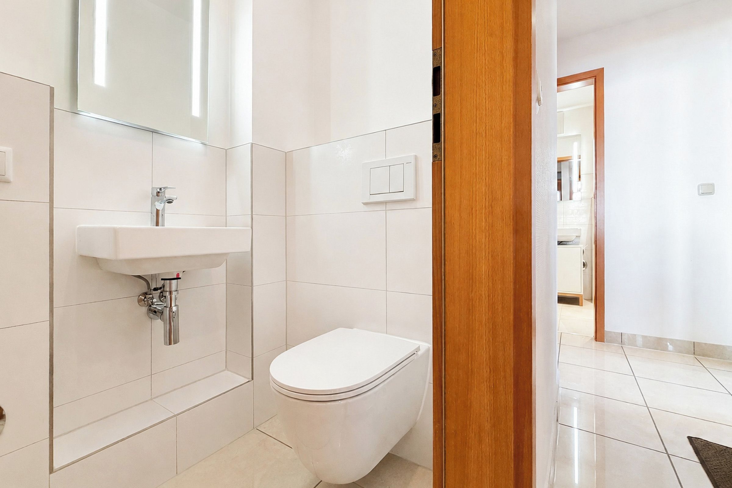 A modern bathroom with a white toilet, a sink, and a mirror.