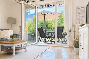 A modern living room with a glass door leading to an outdoor patio area. - Waterkant - Bernstein Wohnung 13 (Ostseebad Boltenhagen)