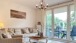 A living room with a striped sofa, a coffee table, and a view of the outdoors through large sliding glass doors.