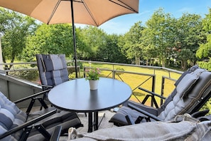An outdoor seating area with a table and chairs, a potted plant, and a large umbrella.