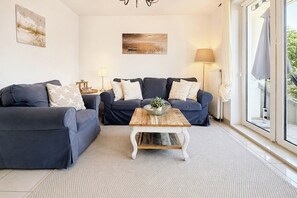 A modern living room with two sofas, a coffee table, and a view of the outdoors.