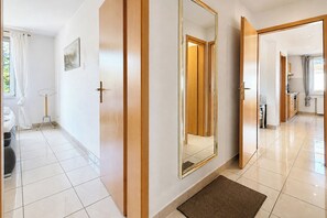 A hotel corridor with a large mirror, wooden doors, and a tiled floor. - Waterkant - Bernstein Wohnung 13 (Ostseebad Boltenhagen)