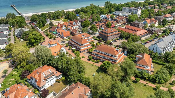An aerial view of a coastal town with traditional European architecture, a beach, and a pier.
